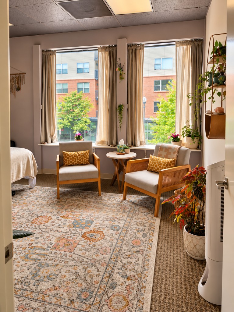 A quiet sitting area with two chairs, plants, and a large window